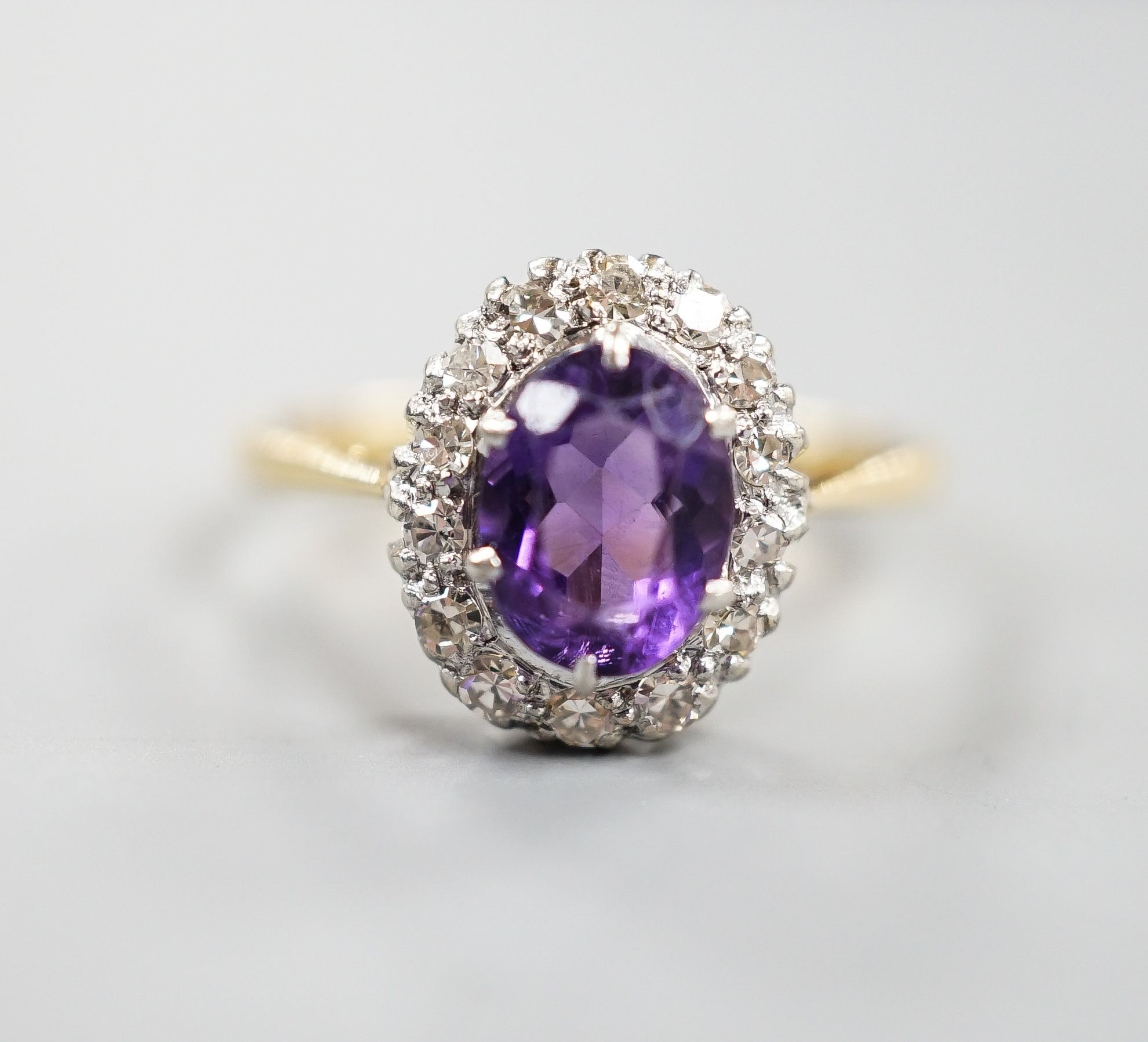 An 18ct, amethyst and diamond set oval cluster ring, size O/P, gross weight 3 grams.